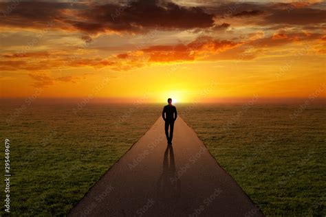 Man Walking Alone On A Road Towards The Sunset Stock Photo Adobe Stock