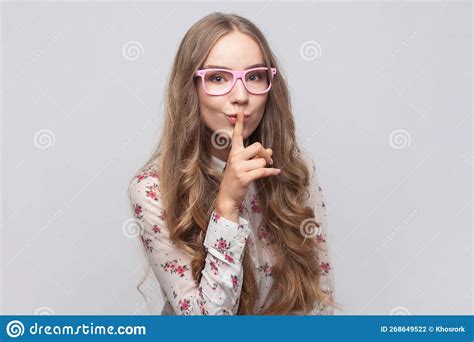 woman showing shh gesture holding finger near lips with naughty smile on face making surprise