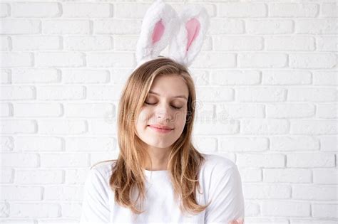 Portrait Of A Happy Woman In Bunny Ears On White Brick Wall Background