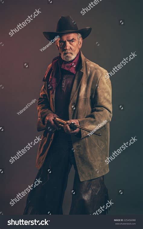 Old Rough Western Cowboy With Gray Beard And Brown Hat Holding Rifle