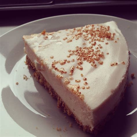 A Piece Of Cheesecake On A White Plate With Sprinkles And Crumbs