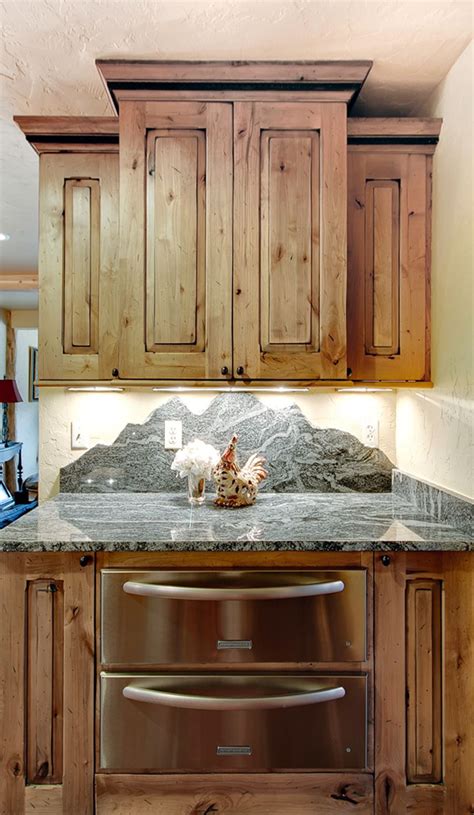 Rangetop nook with alder wood supports beams framing a leathered white marble backsplash over alder wood cabinets accented with nickel drawer pulls topped with leathered marble counters. The color of the cabinets and the mountainous back splash ...
