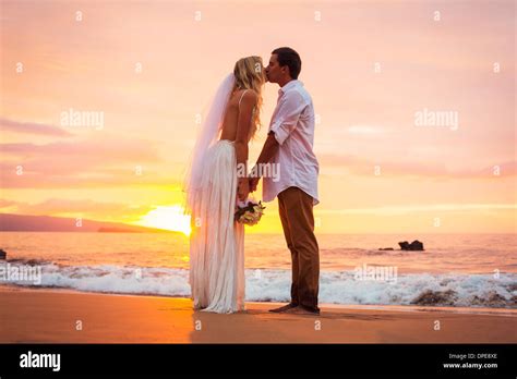 Married Couple Bride And Groom Kissing At Sunset On Beautiful Tropical Beach In Hawaii Stock