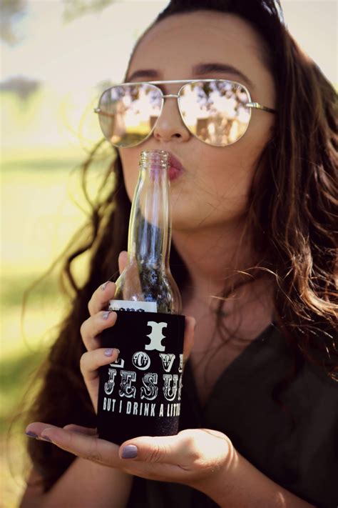 a woman wearing glasses drinking from a bottle with the words jesus not drinking a beer on it