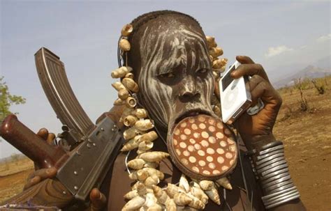 mursi tribeswoman with ipod and ak 47 wired