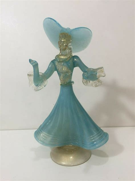 A Glass Figurine With A Blue Dress And Hat