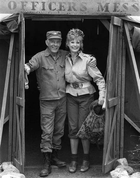 An Old Black And White Photo Of A Man And Woman Standing In Front Of A Door