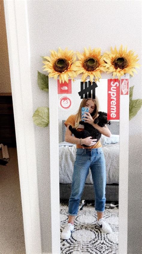 A Woman Taking A Selfie In Front Of A Mirror With Sunflowers On It