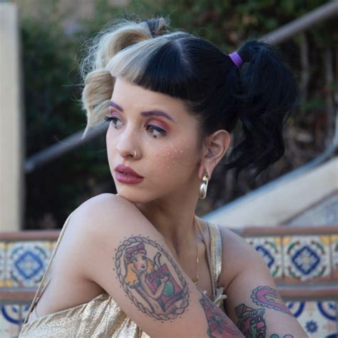 A Woman With Tattoos On Her Arm And Shoulder Sitting In Front Of Some Stairs