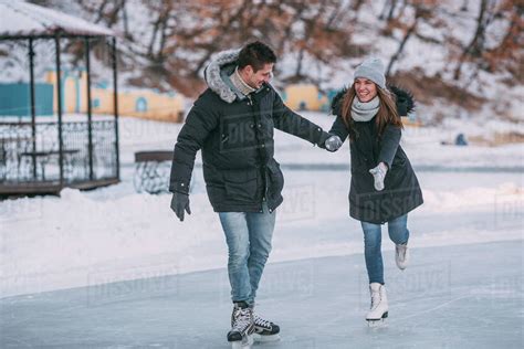 Full Length Of Happy Couple Holding Hands While Enjoying Ice Skating