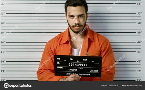 In a Police Station Arrested Man Getting Front-View Mug Shot. He's