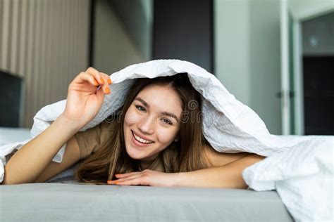 Happy Woman Hiding Under The Duvet In The Bed At Home Stock Photo