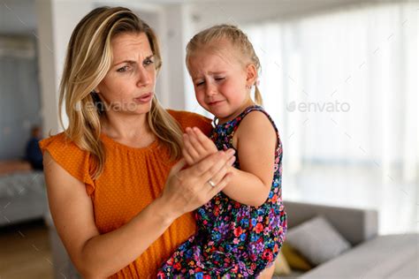 Mother Comforting Her Crying Child After She Hit Her Hand Stock Photo