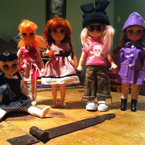 Five Dolls Are Sitting On The Floor In Front Of A Mirror And An Old Key