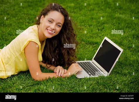 Beautiful Young Woman Lying On The Grass And Working With A Laptop