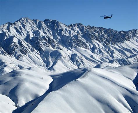 Blackhawk Helicopter Soaring Over Snowy Afghanistan Mountains