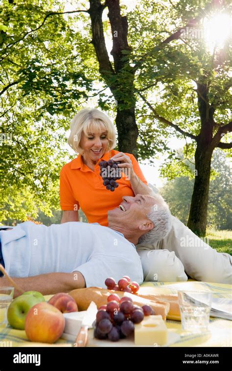 Mature Woman Feeding Man Grapes At Picnic In Park Stock Photo Alamy