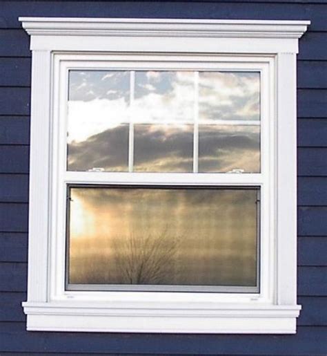 A Window That Is On The Side Of A Blue House With Clouds In The Sky