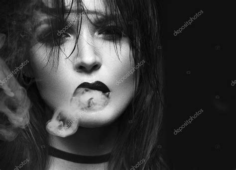 beautiful sexy brunette girl with bright makeup red lips smoke from mouth beauty face black