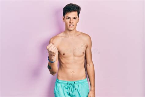 Young Hispanic Man Wearing Swimwear Shirtless Angry And Mad Raising Fist Frustrated And Furious