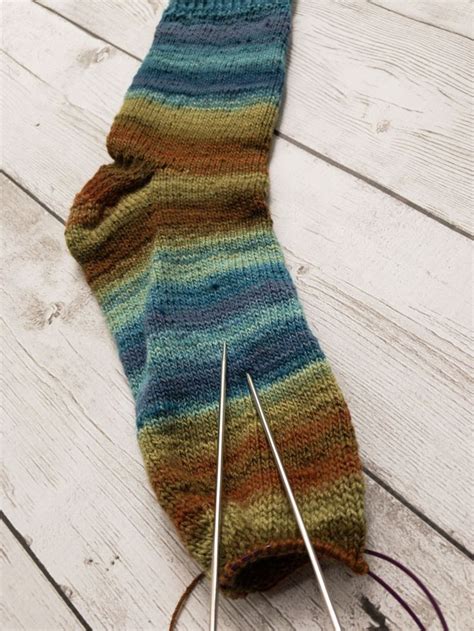 A Pair Of Knitting Needles Sitting Next To A Sock