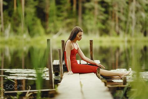 Обои на рабочий стол Девушка в красном сарафане сидит на мостике у воды