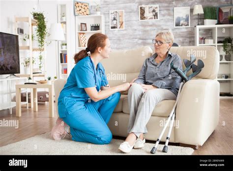 Granny Sitting On A Couch In A Nursing Home Talking With Female Nurse