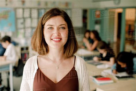 Portrait Of Smiling Female Teacher Standing In Classroom Stock Photo