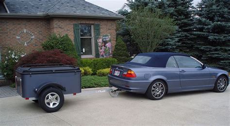 A Car Is Parked Next To A Trailer In Front Of A Brick House With Trees