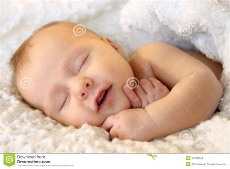 Smiling Sleeping Newborn Baby Girl Wrapped In White