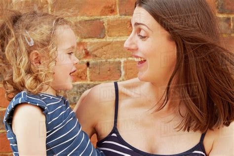Cute Girl And Laughing Mother By Brick Wall Stock Photo Dissolve