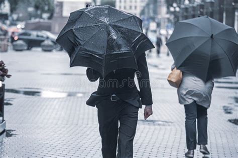 People With Umbrellas Walk Down The Street During The Rain People