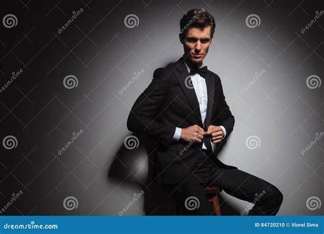 Seated Elegant Business Man In Tuxedo Buttoning His Coat Stock Photo