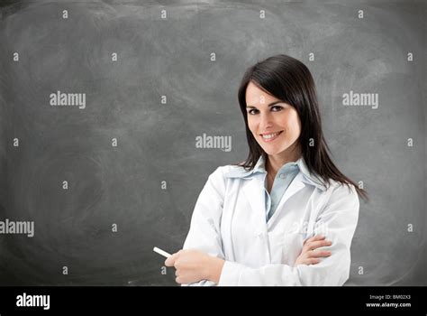 Portrait Of Mid Adult Teacher With Arms Folded Against Blank Blackboard