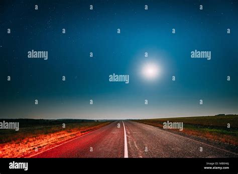 Blue Night Starry Sky With Moon Above Country Asphalt Road In
