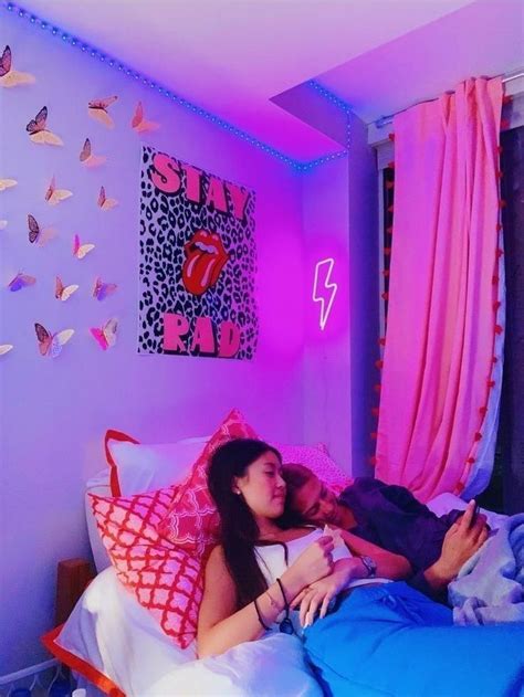 Two People Laying On A Bed In A Room With Pink And Blue Walls