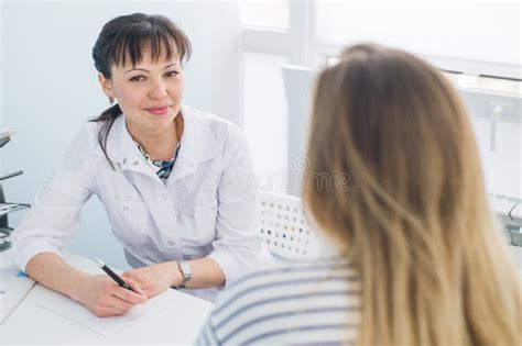 Женский доктор и пациент говоря в офисе больницы Здравоохранение и обслуживание клиента в