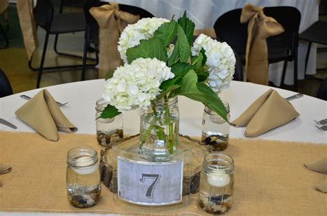 Centerpieces Of Hydrangeas On A Wood Slice With Mason Jars Filled With