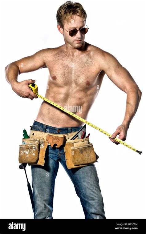 sexy caucasian handyman posing with his toolbelt wearing aviator sunglasses and blue jeans stock