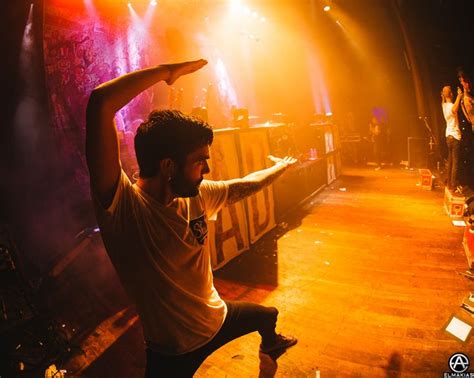 A Man Standing On Top Of A Wooden Floor In Front Of A Stage Filled With People