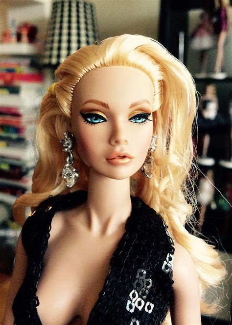 A Barbie Doll With Blonde Hair And Blue Eyes Wearing A Black Dress In A Living Room