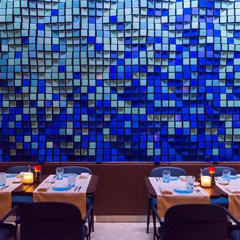 Two Tables With Place Settings In Front Of A Blue Mosaic Tile Wall