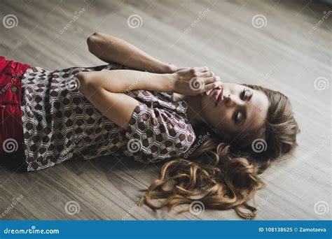 The Girl In Dreams Lies On The Parquet Floor With Podniecenie To Stock