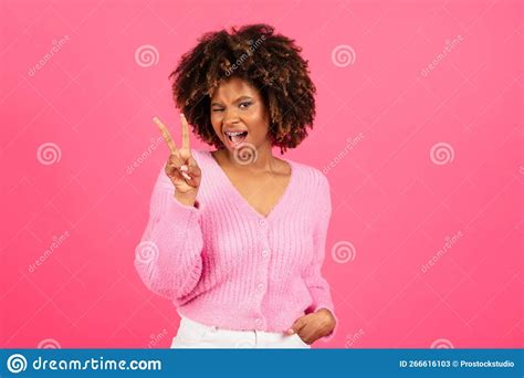 cheerful millennial african american curly woman in casual winks show peace sign with hand