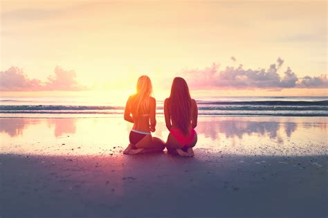 Free Photo Two Young Women Watching The Sunset Over The Ocean Sitting Sensual Seashore