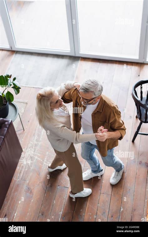 Overhead View Of Smiling Woman Dancing With Elderly Husband Stock Photo