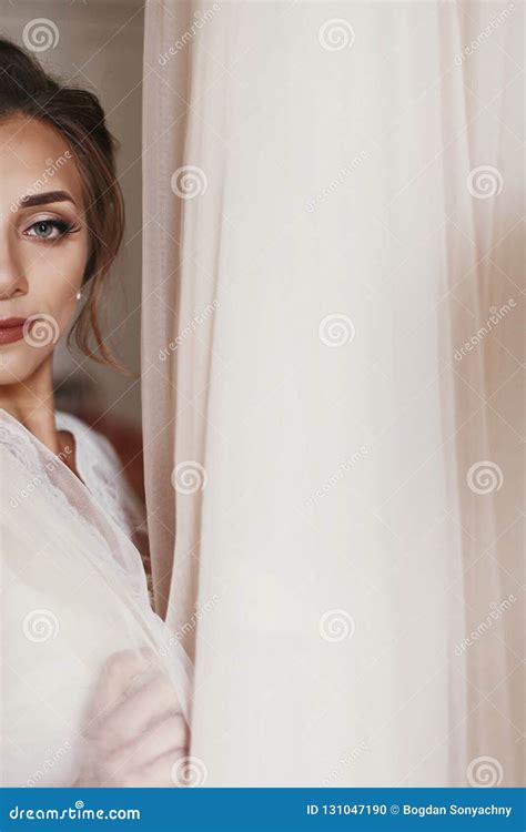 Gorgeous Bride In Silk Robe Holding Stylish Wedding Dress In Room In