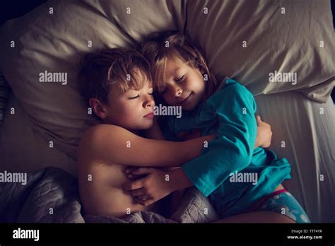 Overhead View Of Loving Siblings Sleeping Together On Bed At Home Stock
