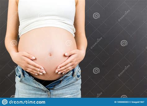Close Up Of Naked Pregnant Woman`s Belly Wearing Opened Jeans At