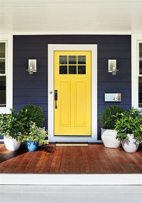 Two Potted Plants Sit On The Front Porch Of A Blue And White House With